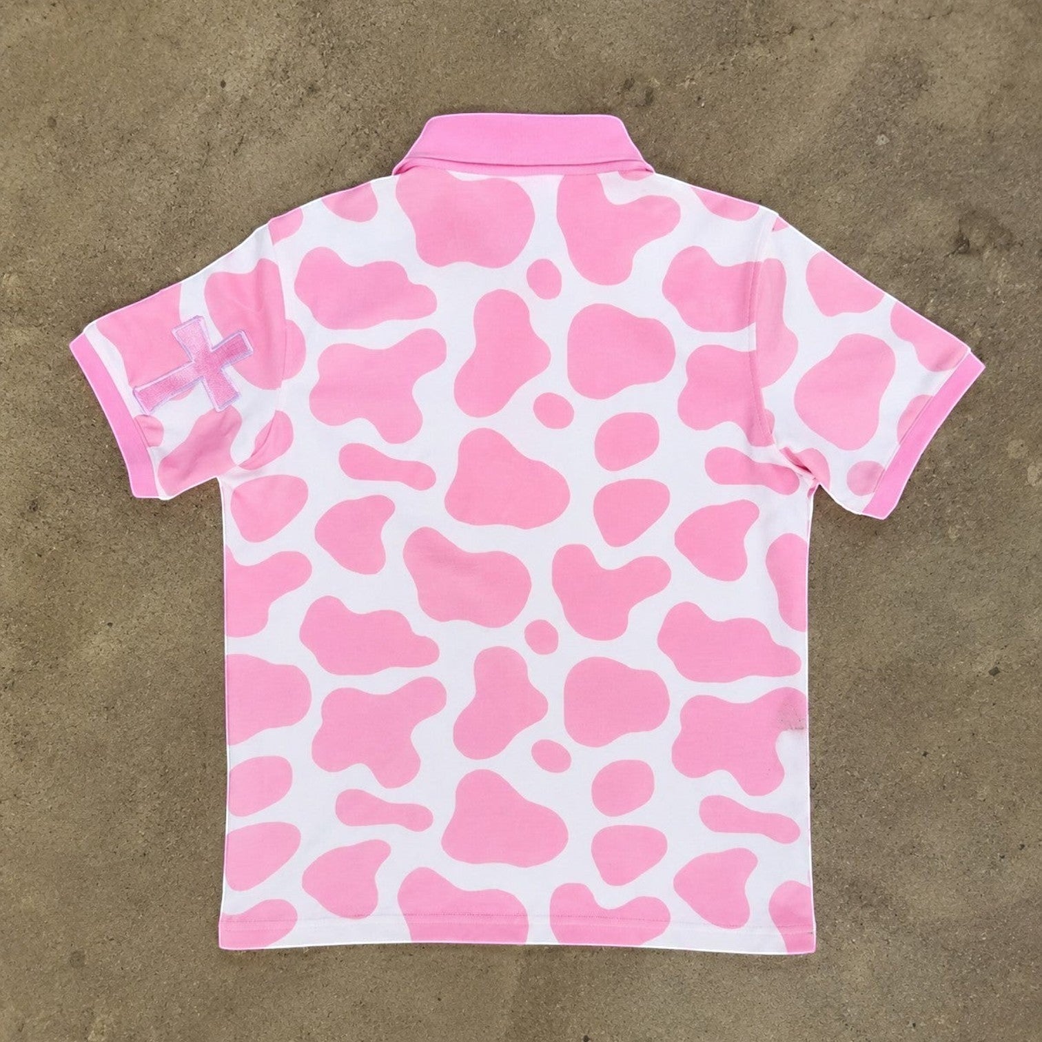 JR's Strawberry Milk polo shirt in pink and white cow print pique knit with embroidered cross detail on the sleeve.